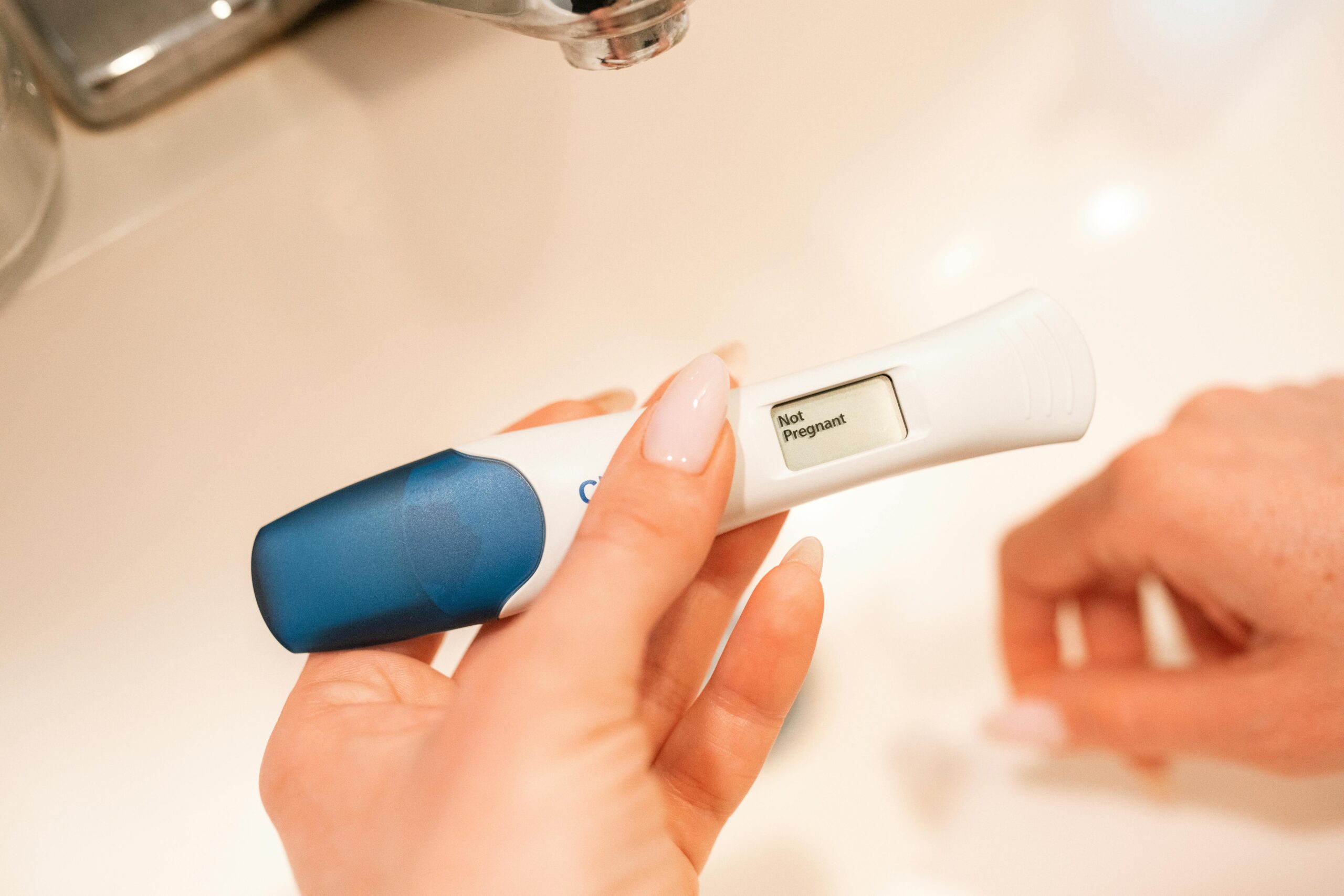 A woman holding a pregnancy test in her hand. The result says, 'Not Pregnant'. The image shows a negative pregnancy test after frozen embryo transfer.
